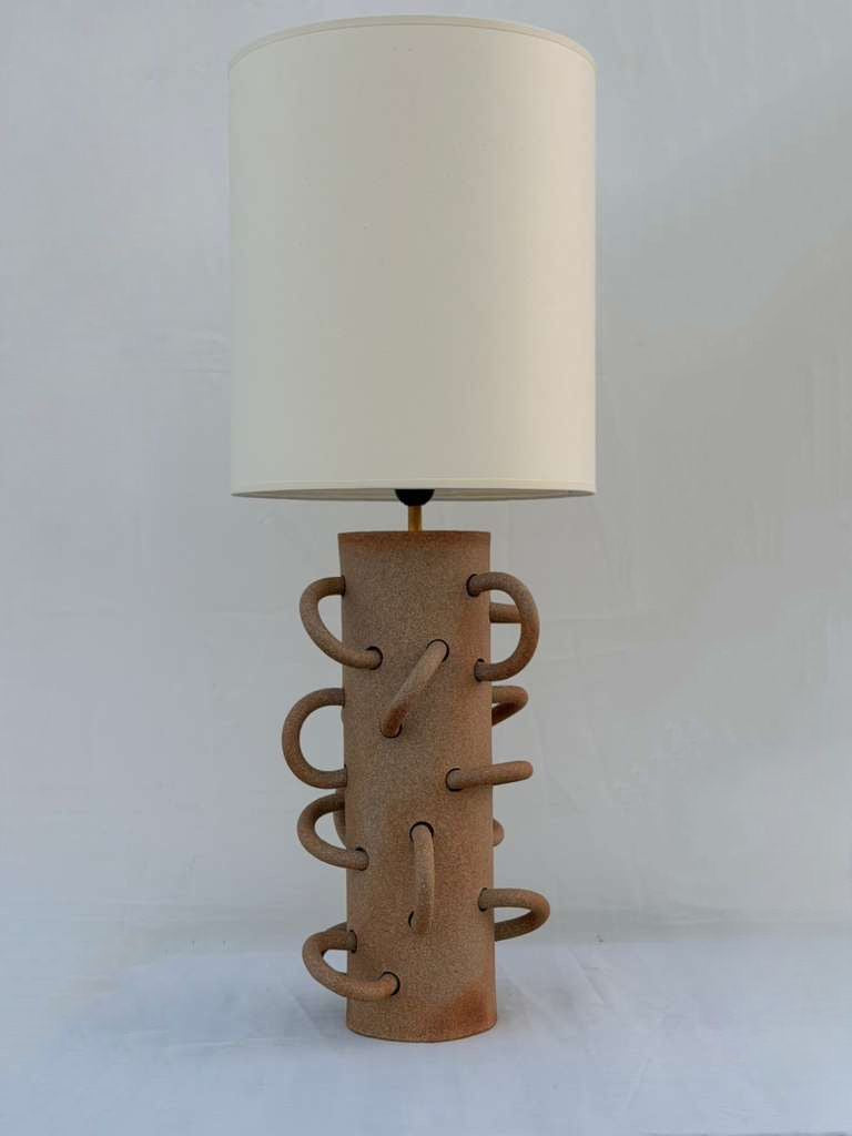 Unglazed Loop Lamp in sand, with off-white cotton paper shade. 